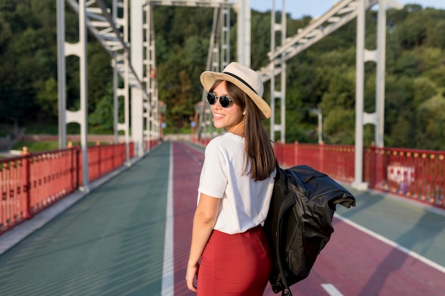 Free photo side view of woman with sunglasses and hat posing while traveling alone